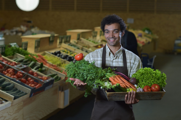 Grocery clerk working in produce aisle of supermarket store - Photo, Image