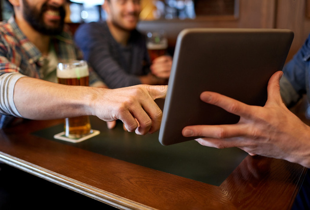 close up of men with tablet pc and beer at bar - Фото, зображення