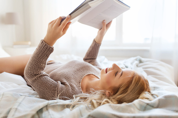 young woman reading book in bed at home - Photo, Image