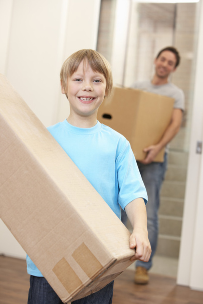 Boy with young man on moving day carrying cardboard box - 写真・画像