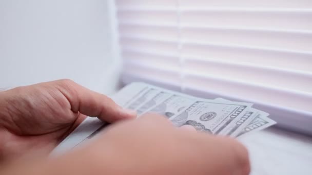 Κοντινό πλάνο του μια businessmans χέρια μετρώντας εκατοντάδες λογαριασμούς δολαρίων σε ένα τραπέζι - Πλάνα, βίντεο