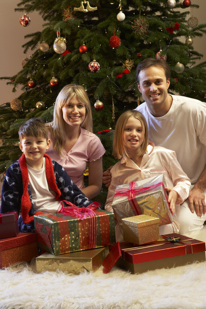 Family Opening Christmas Present In Front Of Tree - Foto, imagen