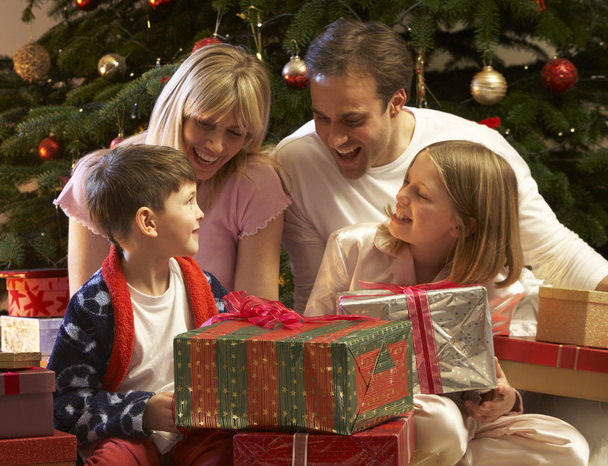Family Opening Christmas Present In Front Of Tree - Valokuva, kuva