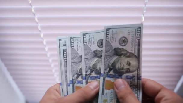 Κοντινό πλάνο του μια businessmans χέρια μετρώντας εκατοντάδες λογαριασμούς δολαρίων σε ένα τραπέζι - Πλάνα, βίντεο