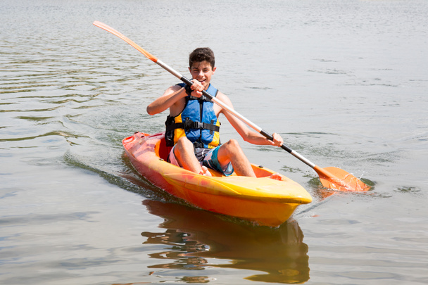 Feliz joven remando en el lago en kayak y sonriendo
 - Foto, Imagen