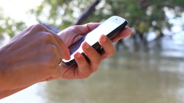 Gros plan de l'homme mains en utilisant Smartphone, fond de la nature
. - Séquence, vidéo
