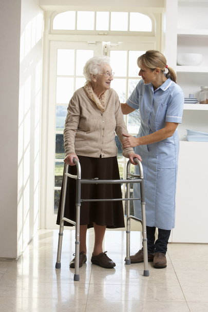Carer Helping Elderly Senior Woman Using Walking Frame - Fotó, kép