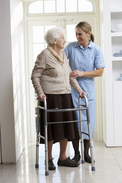 Carer Helping Elderly Senior Woman Using Walking Frame - 写真・画像
