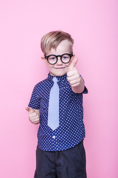 Portrait of a little smiling boy in a funny glasses and tie. Ok. School. Preschool. Fashion. Studio portrait over pink background - Photo, Image