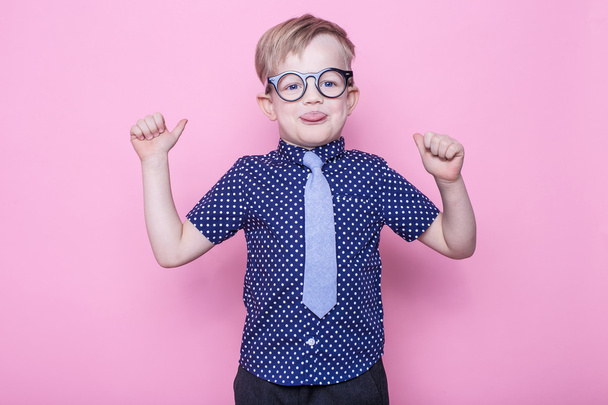 Pienen hymyilevän pojan muotokuva hassuissa laseissa ja solmiossa. Kouluun. Esikoulu. Muotia. Studio muotokuva vaaleanpunainen tausta
 - Valokuva, kuva
