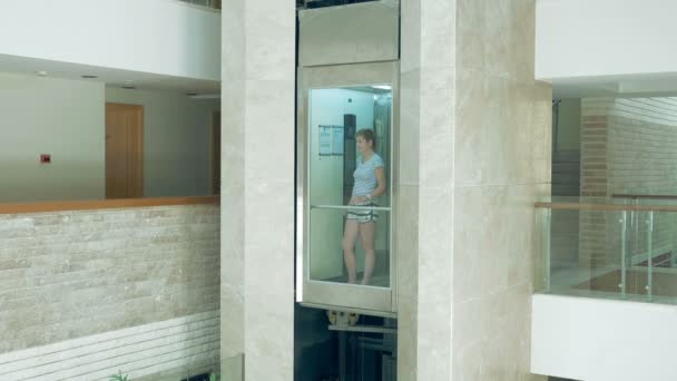 Una hembra está de pie en vidrio elevador en movimiento
 - Metraje, vídeo