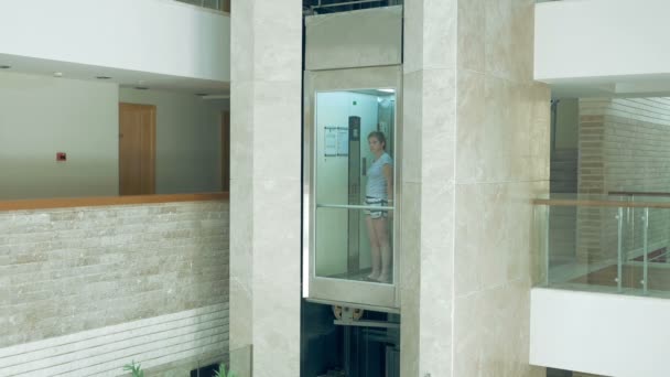 Uma fêmea está de pé no elevador em movimento de vidro
 - Filmagem, Vídeo