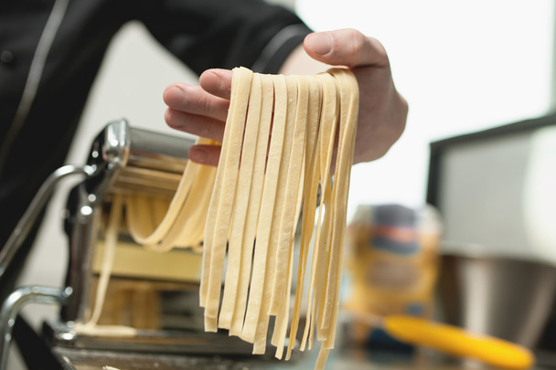 human hand with pasta from machine; - Photo, Image