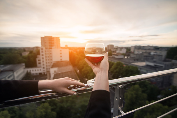 female's hand keep glass with wine in hand in rays of sunset; - Foto, immagini