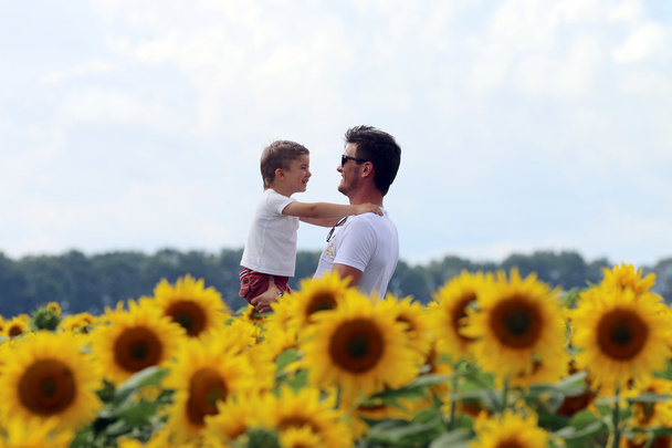 счастливый счастливый отец со своим милым умным воспитанным сыном на поле цветущего подсолнуха
 - Фото, изображение