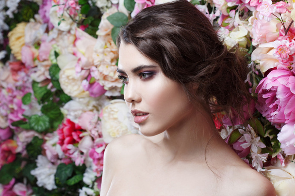 Profile of beautiful fashion girl, sweet, sensual. Beautiful makeup and messy romantic hairstyle. Flowers background. - Foto, afbeelding
