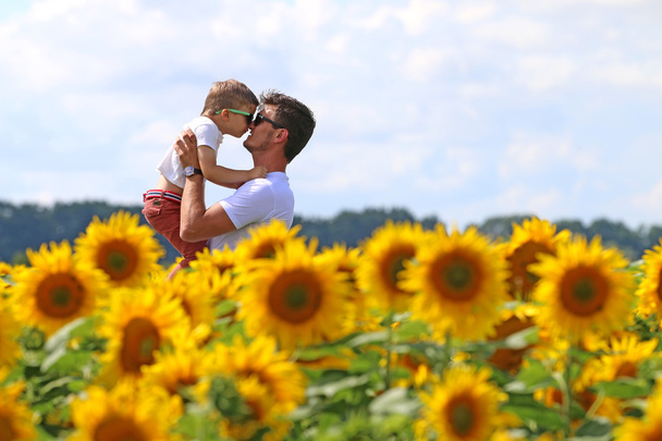 joyfull szczęśliwy ojciec z jego ładny mądry syn dobrze wychowany w dziedzinie kwitnących słonecznika - Zdjęcie, obraz