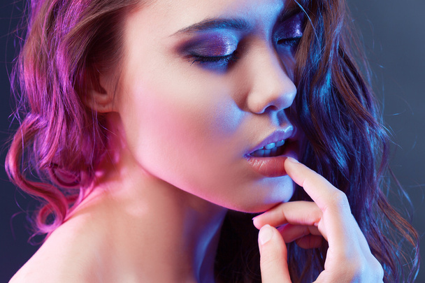 Portrait of young beautiful girl brunette, amid spotlight. The effect toning, night club, dance culture - Фото, изображение