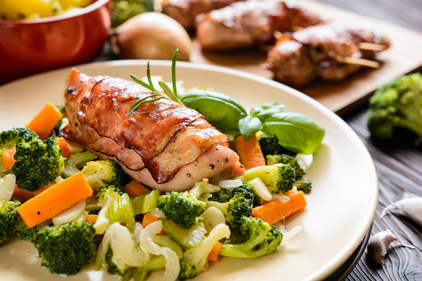 Baked chicken breast wrapped in bacon with boiled potatoes and steamed vegetable garnish - Photo, Image