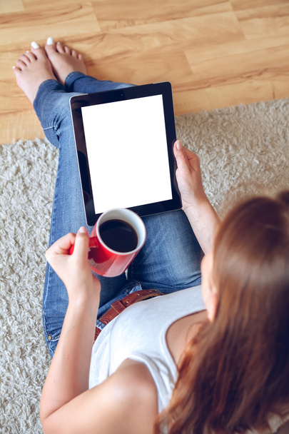 Woman sitting on the couch with tablet and coffee in hand - Foto, imagen