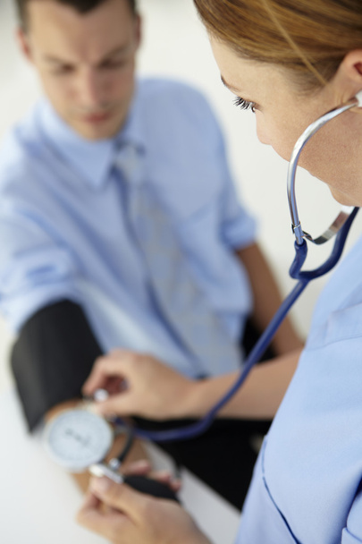 Doctor taking young man's blood pressure - Фото, зображення