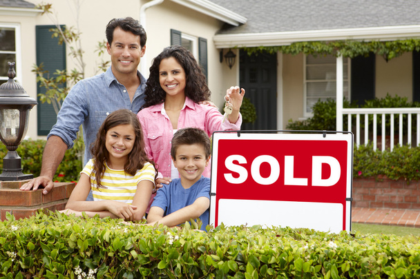 Hispanic family outside home with sold sign - Foto, imagen