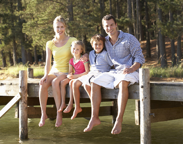 Young family sitting by lake - Foto, imagen