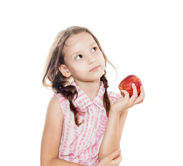 little girl with braids holding red apple, looking up and thinki - Photo, Image