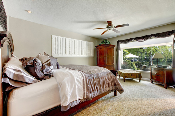Elegant large bedroom with window and brown furniture. - 写真・画像
