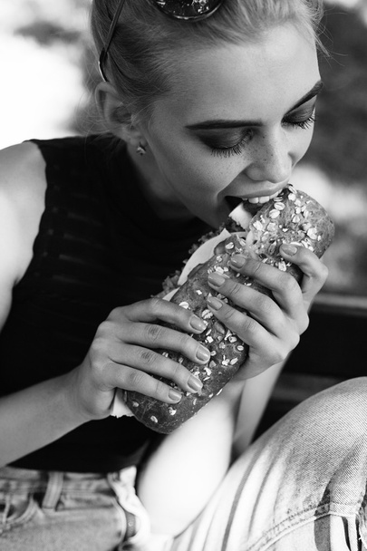 Гіпстер гратчаста позування їсть великий бутерброд
 - Фото, зображення