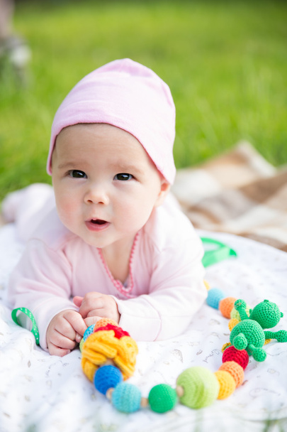 Bebé niña arrastrándose sobre la hierba con perlas de honda
 - Foto, Imagen