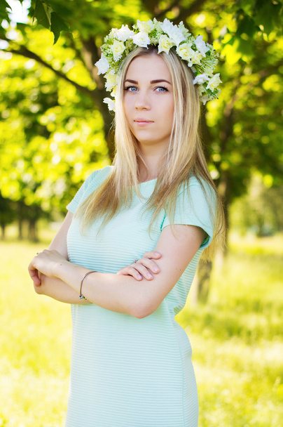 Jeune femme blonde aux yeux bleus et aux fleurs sur la tête
  - Photo, image