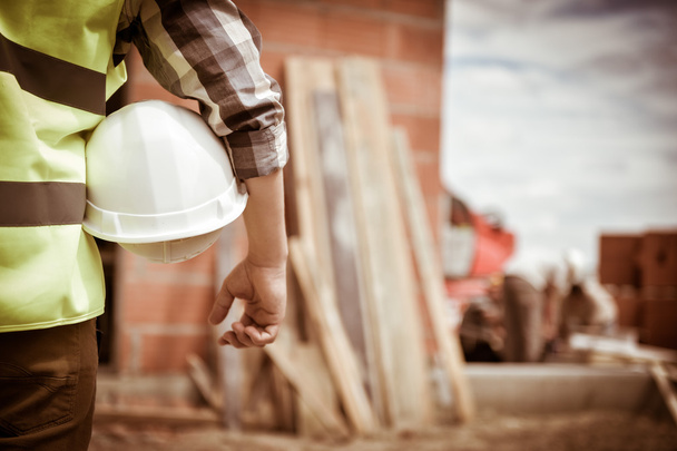 Worker holding a helmet with background of construction site. - Photo, Image
