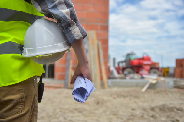 Worker holding a helmet with background of construction site. - Fotografie, Obrázek