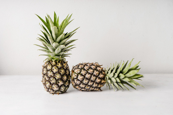 Pineapples on wooden table over white background - Fotoğraf, Görsel