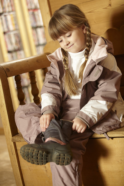 Young Girl Sitting On Wooden Seat Putting On Warm Outdoor Clothe - Foto, Imagem