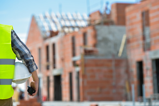 Worker holding a helmet with background of construction site. - Fotografie, Obrázek