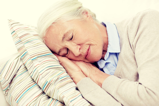 happy senior woman sleeping on pillow at home - Foto, afbeelding
