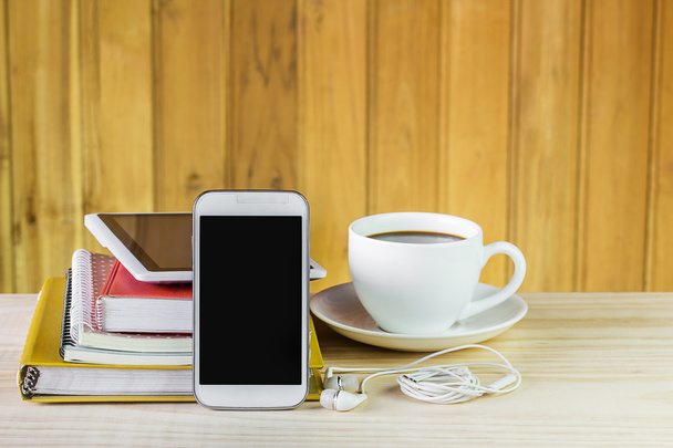 Inteligentny telefon, filiżanki kawy i stos książek na drewnianym stole - Zdjęcie, obraz
