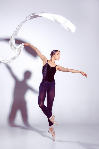 Ballerina in black outfit posing on toes, studio background. - Foto, Imagen
