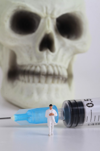 emberi koponya, miniatűr egy orvos, és a fecskendő  - Fotó, kép
