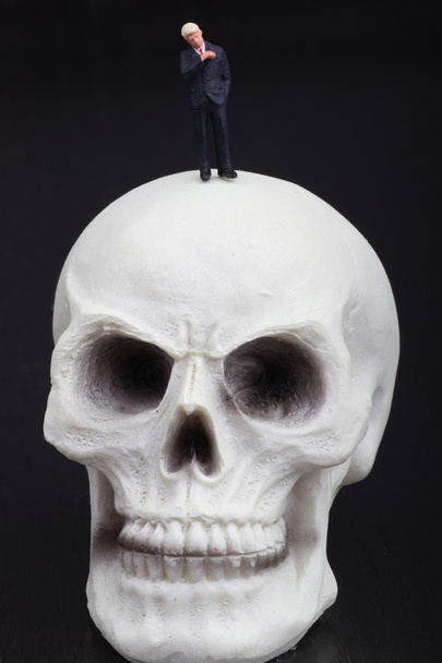 estatuilla miniatura de un hombre de negocios con un cráneo humano
 - Foto, Imagen