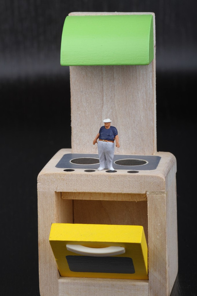 мініатюрна фігурка здорового чоловіка над плитами кухні
 - Фото, зображення
