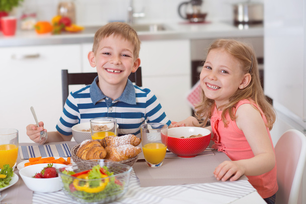 Two happy children having breakfast in kitchen - Foto, Bild