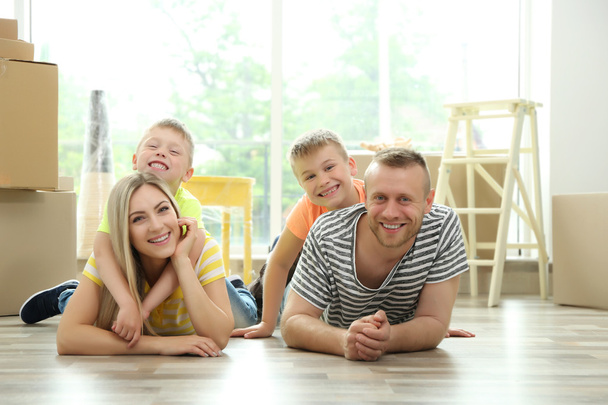 Happy family with cardboard boxes lying on wooden floor - Фото, зображення
