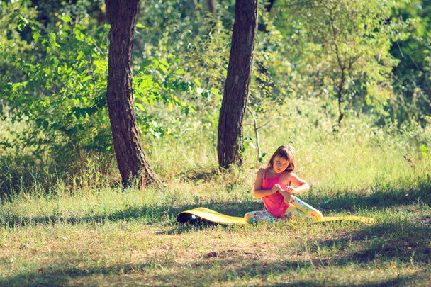 Teenager doing yoga and relaxing by siting in a grass in a park - Photo, Image