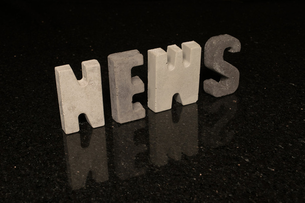 Word News as grey concrete letters on black tile  - Foto, Bild
