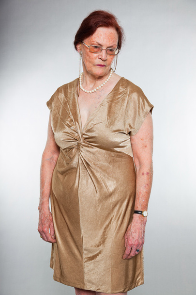 Retrato de una mujer mayor guapa usando gafas con cara expresiva mostrando emociones. Triste. Actuando joven. Estudio plano aislado sobre fondo gris
. - Foto, Imagen