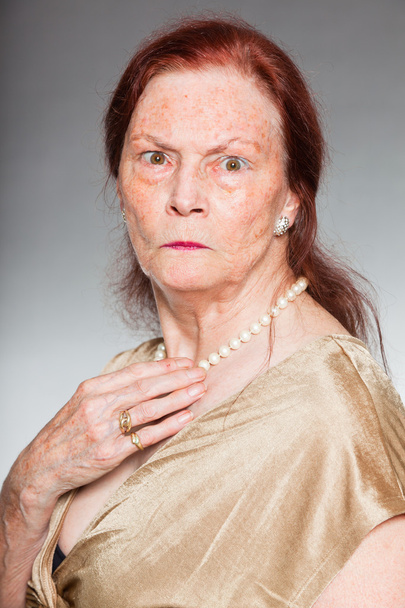 Retrato de una mujer mayor de buen aspecto con cara expresiva mostrando emociones. Enojado. Actuando joven. Estudio plano aislado sobre fondo gris
. - Foto, Imagen