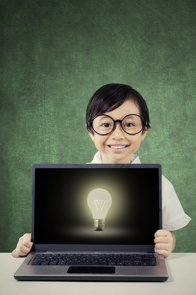Little girl with lightbulb on laptop monitor - Fotó, kép